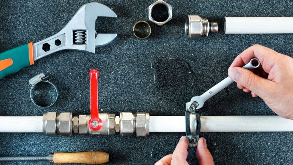 Plumber repairing a pipe valve with an adjustable wrench in Apollo Beach