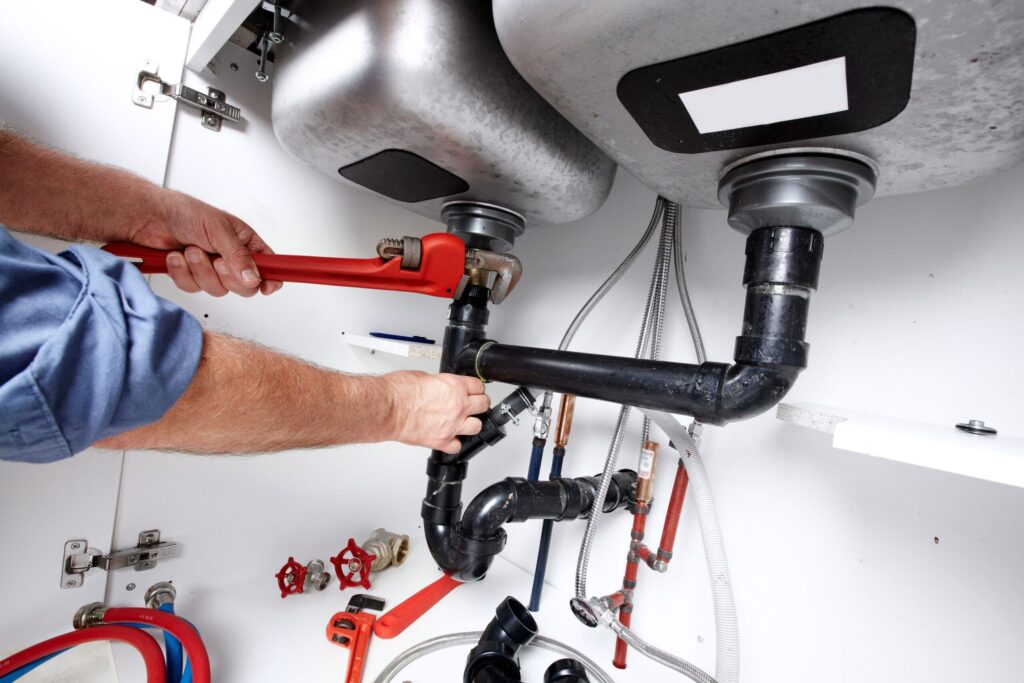 Plumber repairing drain pipes beneath a kitchen sink in Apollo Beach