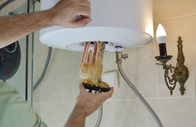 Technician removing mineral buildup from a water heater in Apollo Beach